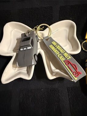 Gray Cartoon Car Keychain with 'Una Ciudad Muy Romantic Car' Tag